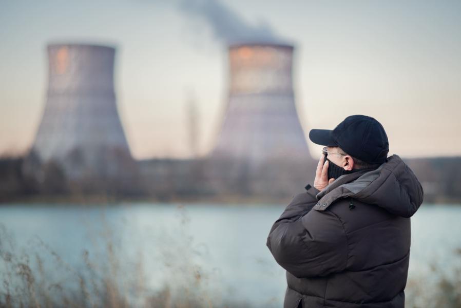 An adult man who is wearing a mask breathes polluted air by the river